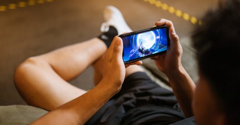 Man playing a video game on a smartphone while sitting comfortably indoors.